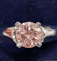 Close-up of ring front showing round pink diamond set in four-prong white gold setting
