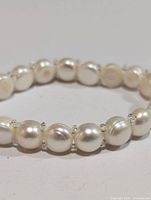 Close-up front view of the fresh water pearl flexible bracelet showing round pearls and clear beads on elastic band.