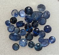 Close-up of multiple faceted blue sapphires showing various shades of blue and cuts.