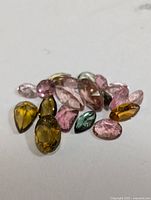Multiple loose tourmaline gemstones of different colors and cuts on a white background.