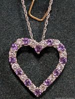 Close-up front view of the heart-shaped pendant showing alternating purple amethyst and clear stones on silver chain.