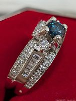 Close-up side view showing blue lab diamond center stone, CZ stones and baguette-cut stones on band