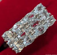 Close-up of the rectangular cluster of oval blue topaz stones set in silver ring under bright lighting.