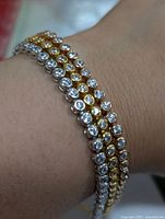 Close-up of the bracelet worn on the wrist showing the silver-tone and gold-tone CZ stones arrangement.