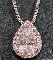 Close-up front view of the silver necklace's pear-shaped CZ pendant showing the large center stone and surrounding smaller stones on a textured background.