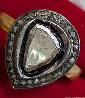 Close-up front view of the silver ring with pear-shaped diamond and surrounding halo diamonds.