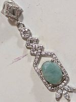 Front view of silver pendant showing oval emerald, geometric CZ setting and marquise CZ cluster at bottom