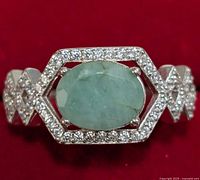 Close-up front view of the silver emerald and cubic zirconia ring showing the oval emerald and hexagonal CZ border design