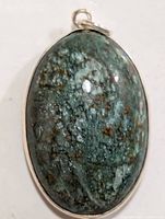 Close-up of the front of the oval-shaped polished gemstone pendant with silver bezel setting and bail loop.
