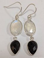 Front view of the silver moonstone and black onyx earrings arranged side by side.