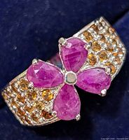 Close-up of the ruby flower centerpiece on the silver ring showing the four pear-shaped stones and surrounding small colored stones