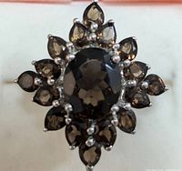 Close-up front view of silver smokey quartz ring showing oval central stone and surrounding pear shaped stones in floral pattern