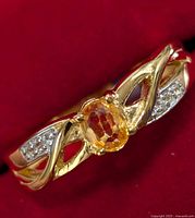 Close-up view of the ring showing the oval yellow sapphire center stone and clear accent stones on the band.