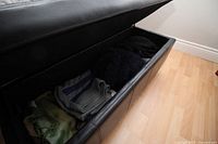 Open storage bench showing interior with folded clothing inside.