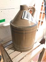 Side view of antique beige ceramic jug with blue and white stripes, showing handle and narrow neck