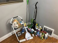 Photo showing entire lot with vacuum, mop, ladder, cleaning supplies arranged on floor near wall