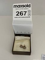 Pair of yellow gold stud earrings in a small jewelry box with auction lot number card behind.