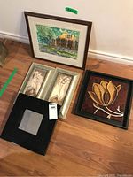 Photo showing all five items: framed watercolour painting, two framed floral prints, gold flower wall art, and black framed mirror on a wooden floor.