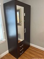 Wardrobe exterior showing dark brown wood finish with full-length mirror on right door and three drawers below.