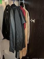 Women's outerwear hanging on a rack, showing various coats, jackets, and a cape in different colors and fabrics.