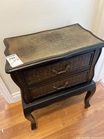 Side view of wooden side table showing drawers and curved legs