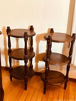 Pair of 1970s Ethan Allen Old Tavern Collection pine 3-tier etagere stand tables in mahogany finish shown side by side on wood floor.