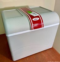 Overall view of light grey Koolatron personal cooler showing exterior and lid with red and white center stripe and Koolatron badge.