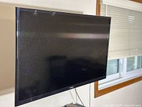 Samsung TV screen against wall, showing the device's black frame and power cable.