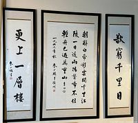Triptych wall art of Chinese calligraphy in three black frames under glass showing all three panels hung on a wall.