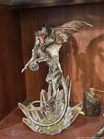 Front view of silver-coloured dragon statue perched on a clear faceted crystal base