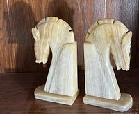 Front side view of two vintage carved onyx horse head bookends, showing detailed horse heads and block bases.