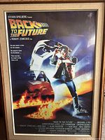 Framed Back to the Future movie poster showing Marty McFly with the DeLorean and flames, with the typical vibrant colors of the poster.