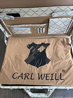 Inside view of stylish textured carrying case with beige diamond pattern and brown cushion with Carl Weill logo printed in black.
