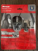 View of Microsoft Wireless Mobile Mouse 3000 in original packaging including USB receiver and extension adapter, black and grey color, packaging compatible with Windows 7