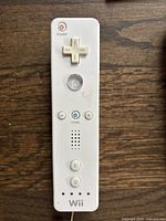 Full view of one Nintendo Wii remote showing button layout including power, D-pad, A button, plus and minus buttons, home button, speaker, number 1 and 2 buttons, and Wii branding