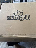 Closed original box showing NutriGrill branding with minor wear