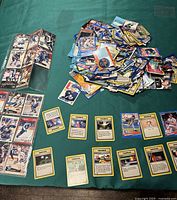 Image showing scattered Pokémon cards with yellow borders and Trainer card titles, displaying both front and back designs with Poké Balls visible.