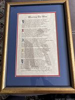 Framed poem titled "Wearing The Blue" with visible text and ornate initial letters, mounted on blue matte inside a gold wooden frame.