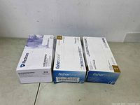 Three boxes of examination gloves from Ocean Pacific and Fisherbrand brands placed side by side showing unopened box condition.