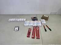 Overview shot of all items laid out on table including automotive parts boxes, pliers, drill bits, and small boxed parts