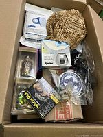 Top-down view of box with assorted boxed items including glass figurine, cable, and kitchenware.