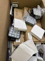 View inside box showing LED square light panels, white cardboard packaging, and assorted small electronic parts.