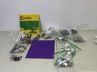 Full lot view showing yellow Lego Classic box, purple base plate, and multiple sealed bags of Lego pieces spread out on surface