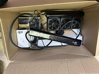 Box interior showing black power strip, cooling fan unit, and cables bundled together.