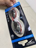 Front view of Speedo Vanquisher 2.0 racing goggles in black and red with clear lenses in original packaging.