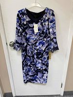 Full front view of the Laura dress hanging on a hanger, showing the floral pattern and 3/4 length sleeves.