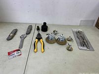 Photo showing all tools laid out including utility knives, wrench, pliers, screwdrivers, hex socket, wire brushes, and packaged metal tool.