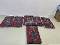 Six new Chef Works aprons in packaging laid out on a floor against a wall