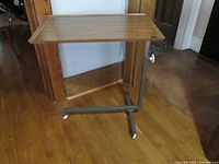 Side view of the articulating bedside/TV tray table showing wood veneer top, metal frame, and casters