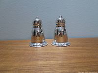 Front view of matched pair of sterling silver shakers showing design and finish.